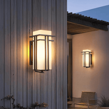 The lantern lit on vertical wood siding, a second one on a covered patio with a chair
