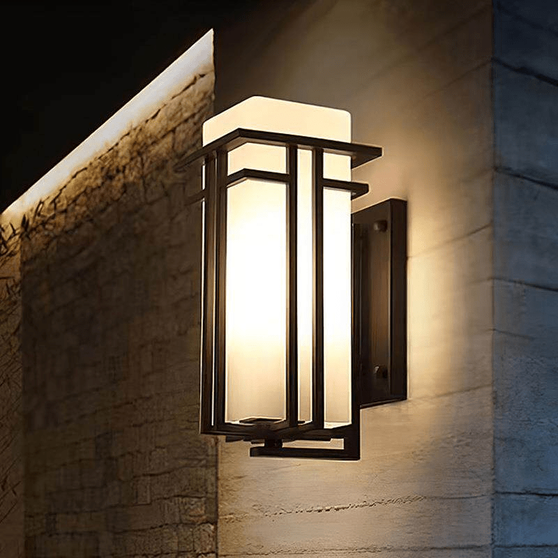 The lantern lit at night on a rough stone corner, the light grazing the texture
