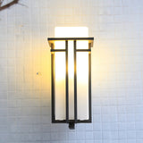 The lantern lit on a white tiled wall, the black bars crossing the glass