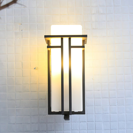 The lantern lit on a white tiled wall, the black bars crossing the glass
