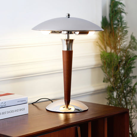 Chrome dome table lamp lit on a console with books and a plant