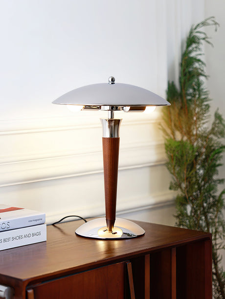 Chrome dome table lamp lit on a console table beside a green plant