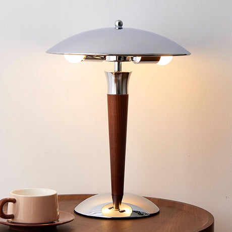 Chrome dome table lamp lit on a round table with mugs beside it