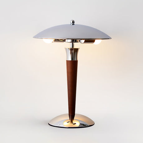 Chrome dome table lamp lit on a round table beside a plant
