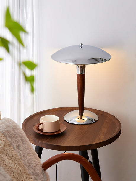Chrome dome table lamp on a round side table with cups and a plant
