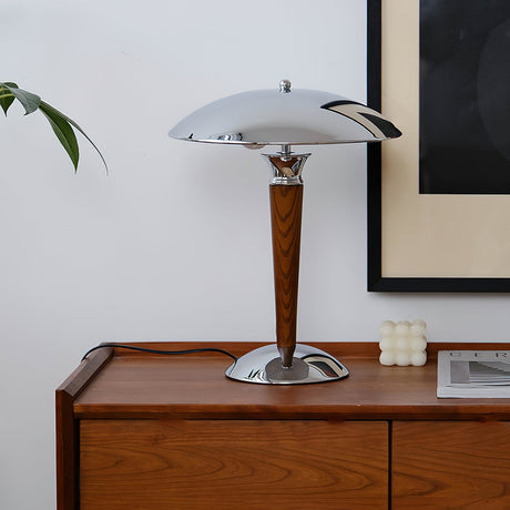 Chrome dome table lamp lit on a sideboard beside candles and frames