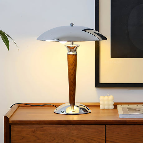 Chrome dome table lamp lit on a sideboard beside a framed picture