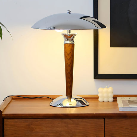 Chrome dome table lamp lit on a sideboard against a pale wall
