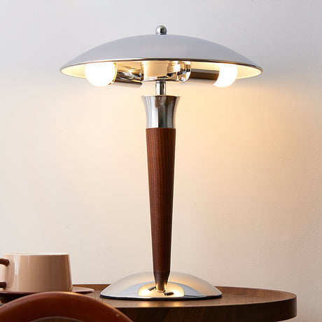 Chrome dome table lamp lit on a table set with mugs