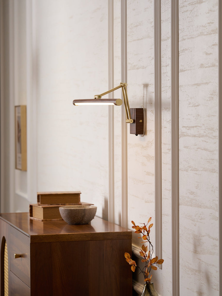 Bar lit above a walnut cabinet with a bowl and dried stems in a quiet corner