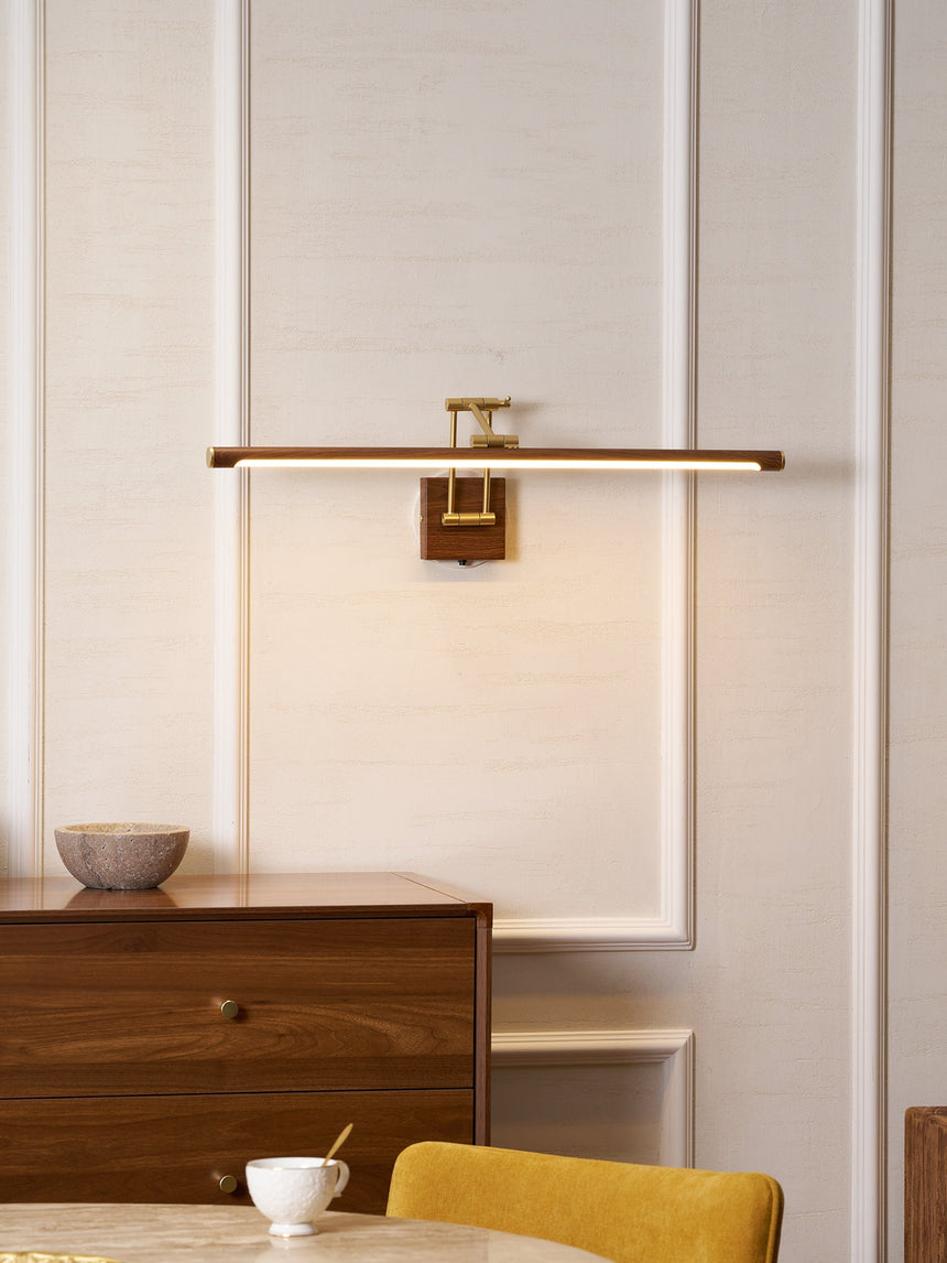 Bar lit on a stone wall above a walnut desk with a bowl and a yellow chair