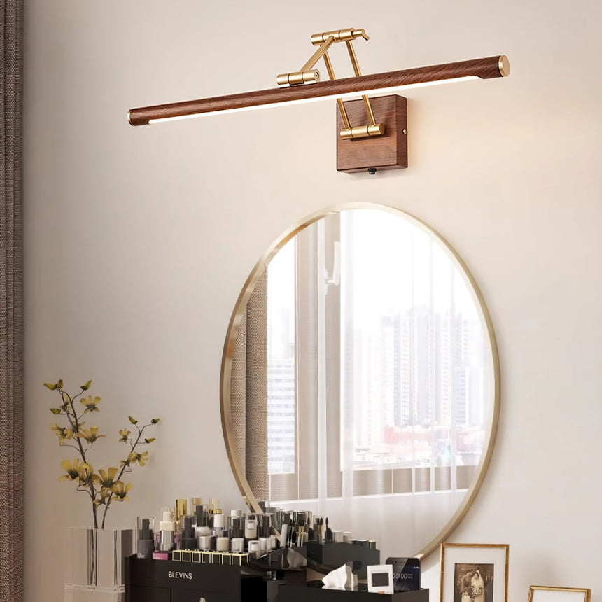 Bar lit above an oval mirror on a dressing table with bottles and a framed picture