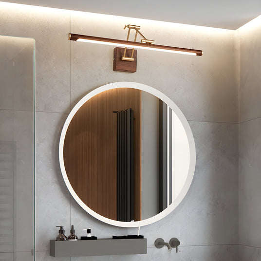 Walnut toned bar lit above a round mirror on a wood panel over a stone basin