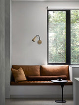 Sconce on a wall above a window bench with a leather seat and cushion