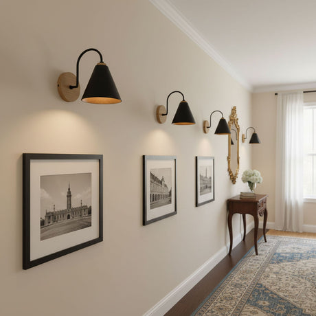Three sconces lit along a hallway wall above framed prints and a console