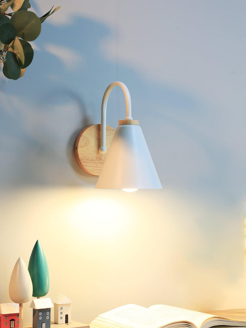 White cone lit above an open book on a desk beside a small plant