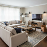 Sconces lit above a sectional sofa beside a low cabinet and a rug