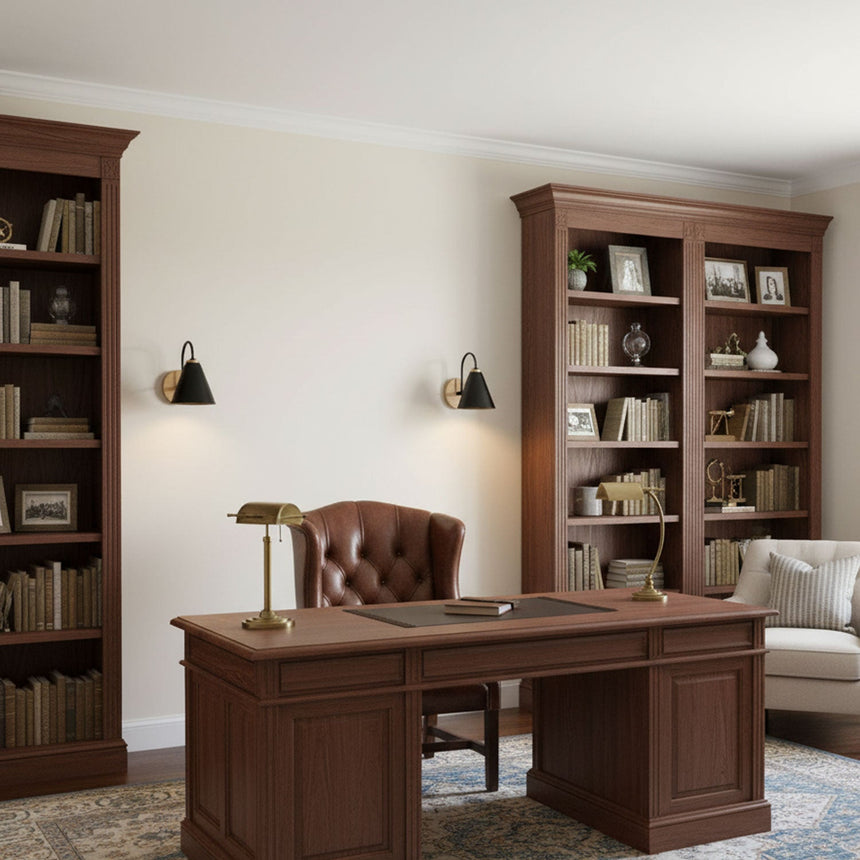 Sconces lit in a study beside a bookcase, a leather chair and a desk