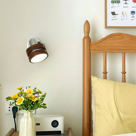 Sconce lit beside a spindle bed above a table with a radio and flowers