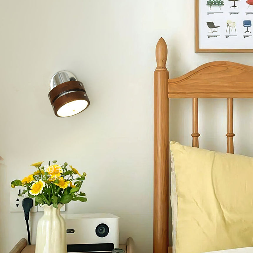 Sconce lit beside a spindle bed above a table with a radio and flowers