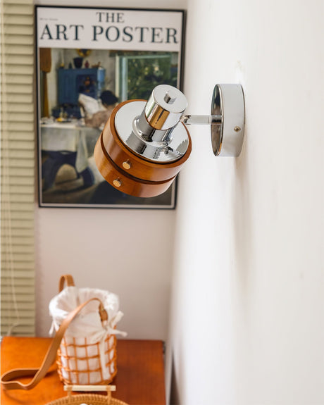 Sconce lit beside a poster above a console with a checked cloth and a jug