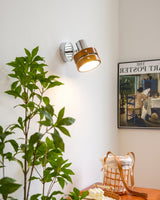 Sconce lit in a corner beside a tall plant and a framed poster on the wall
