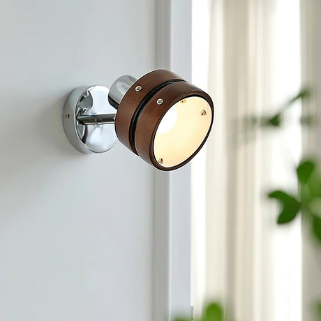 Sconce lit on a pale wall beside a window with a plant in the corner