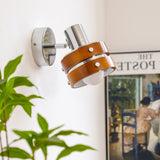 Sconce lit beside a framed poster with a plant leaning into the corner
