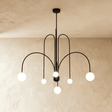 A black chandelier of arched arms each ending in a round opal glass globe