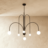 A black chandelier of arched arms each ending in a round opal glass globe