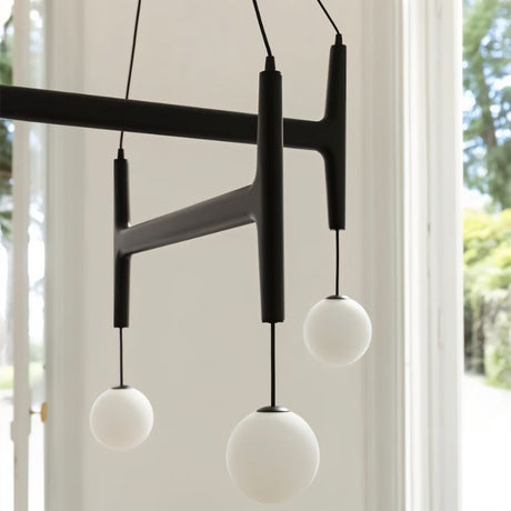 Two globes on the black bar seen close, with a window and greenery behind