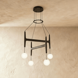 The same crossed bar frame in black wood carrying four lit milk glass globes