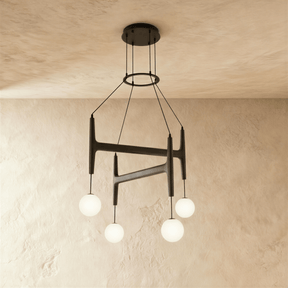 The same crossed bar frame in black wood carrying four lit milk glass globes