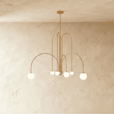 The same arched frame in gold, six opal glass globes hanging at mixed heights
