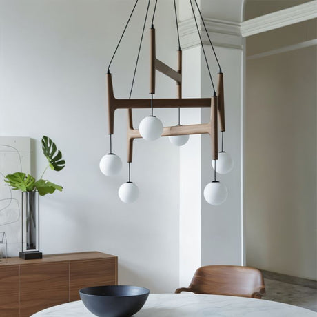 The walnut version lit over a round table with a bowl, a chair and a wood sideboard