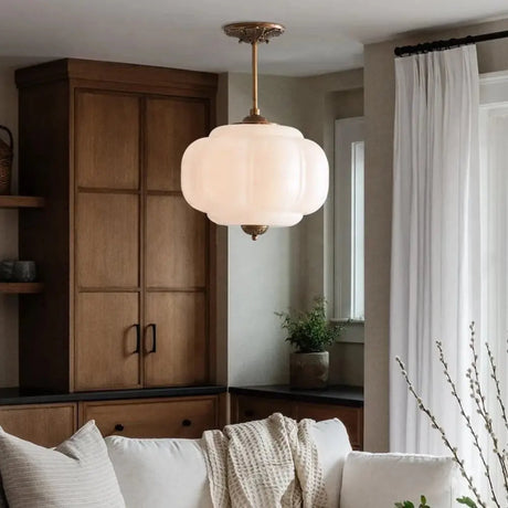 White ribbed shade above a pale sofa with a tall wooden cabinet behind