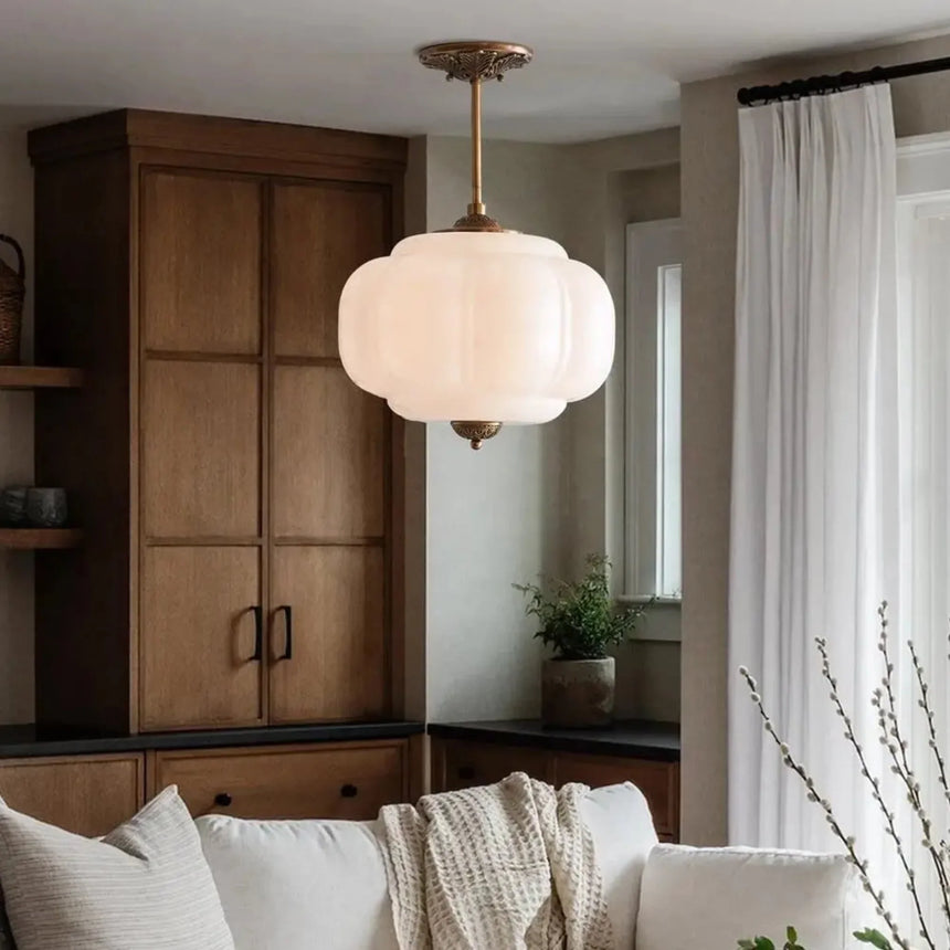 White ribbed shade above a pale sofa with a tall wooden cabinet behind