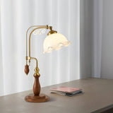 Brass arch lamp lit on a gray desk beside a stack of magazines