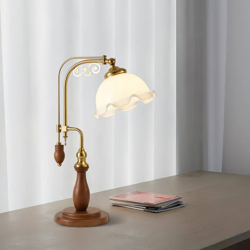 Brass arch lamp lit on a gray desk beside a stack of magazines