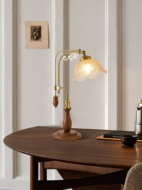 Brass arch lamp lit on a dark wood table beside a chair and a frame
