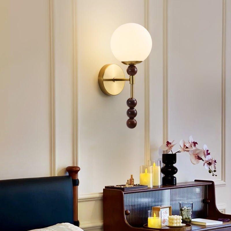 Milk glass globe lit on a paneled bedroom wall above a wood cabinet