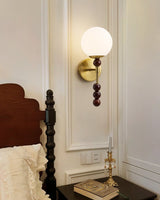 Milk glass globe lit beside a dark wood headboard on a paneled wall