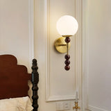 Milk glass globe lit warm on a brass plate with walnut beads below it