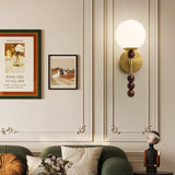 Milk glass globe lit on a paneled wall beside two framed prints