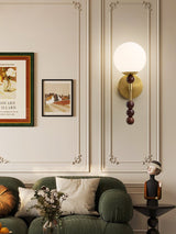 Milk glass globe lit above a green sofa on a paneled living room wall