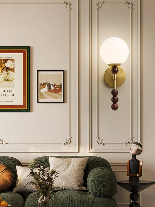 Milk glass globe lit above a green sofa on a paneled living room wall
