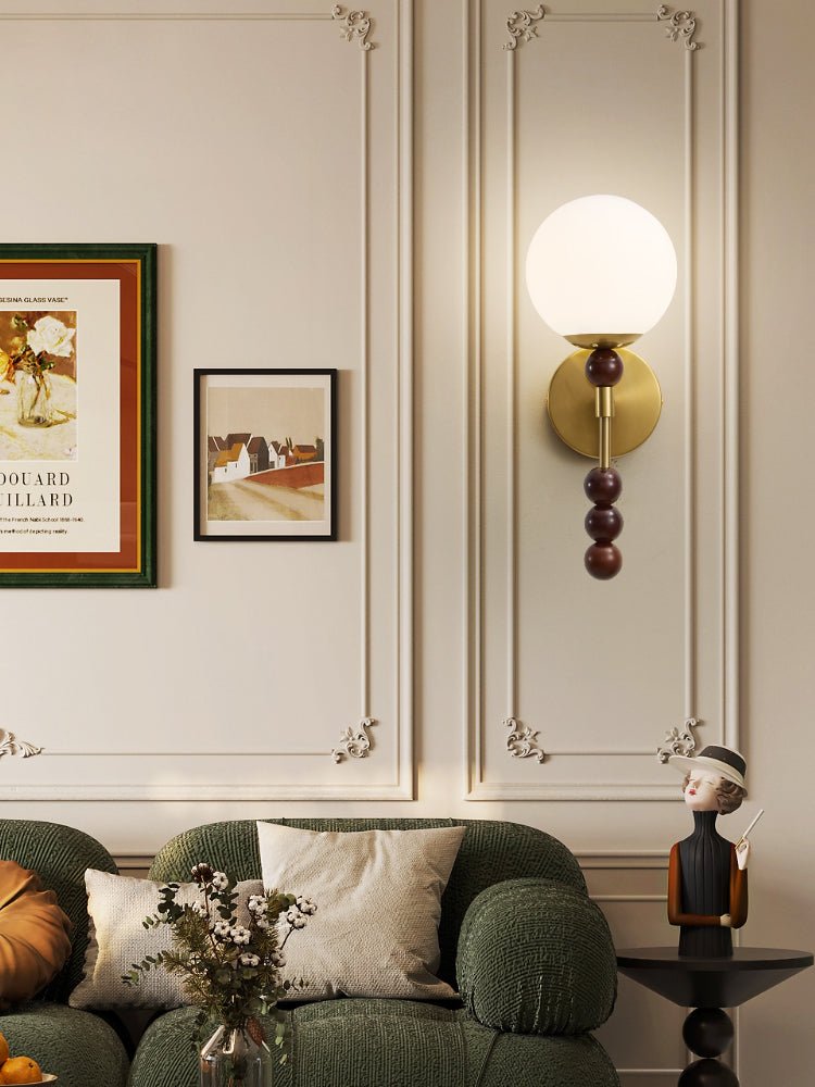 Milk glass globe lit above a green sofa on a paneled living room wall