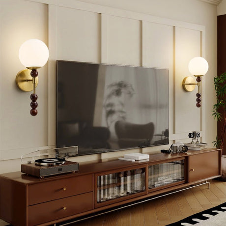 A pair of milk glass globes lit on either side of a wall mounted screen