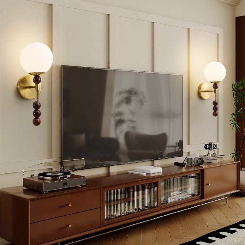 A pair of milk glass globes lit on either side of a wall mounted screen
