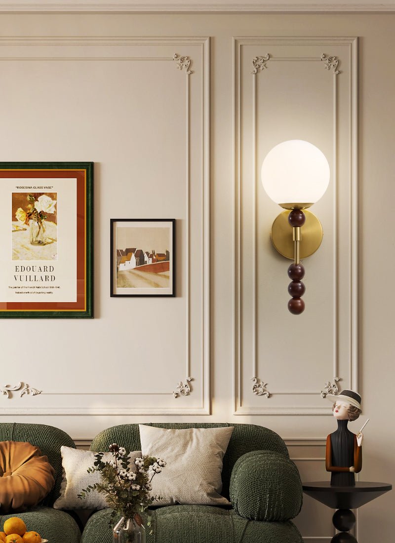Milk glass globe lit high on a paneled wall above framed artwork